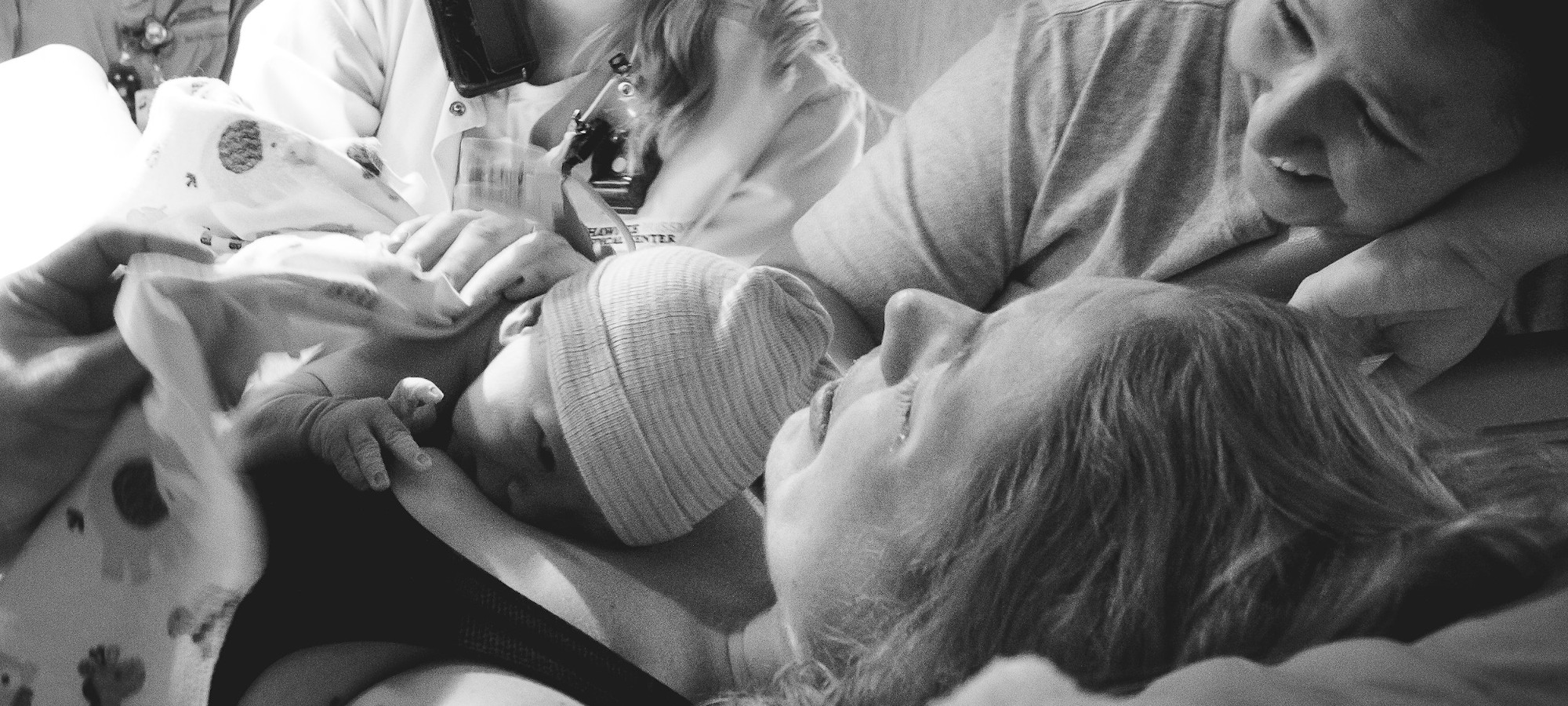 A mother holding her newborn baby while being attended to by her doula.