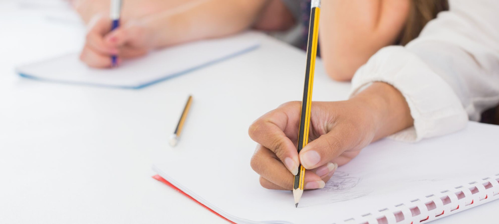 Close-up photos of people writing in notepads with pencils