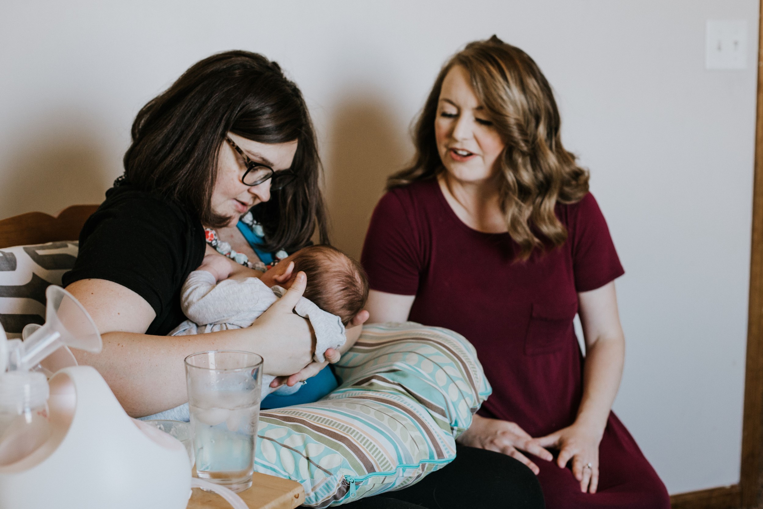 A mother holding her newborn baby while being attended to by her doula.