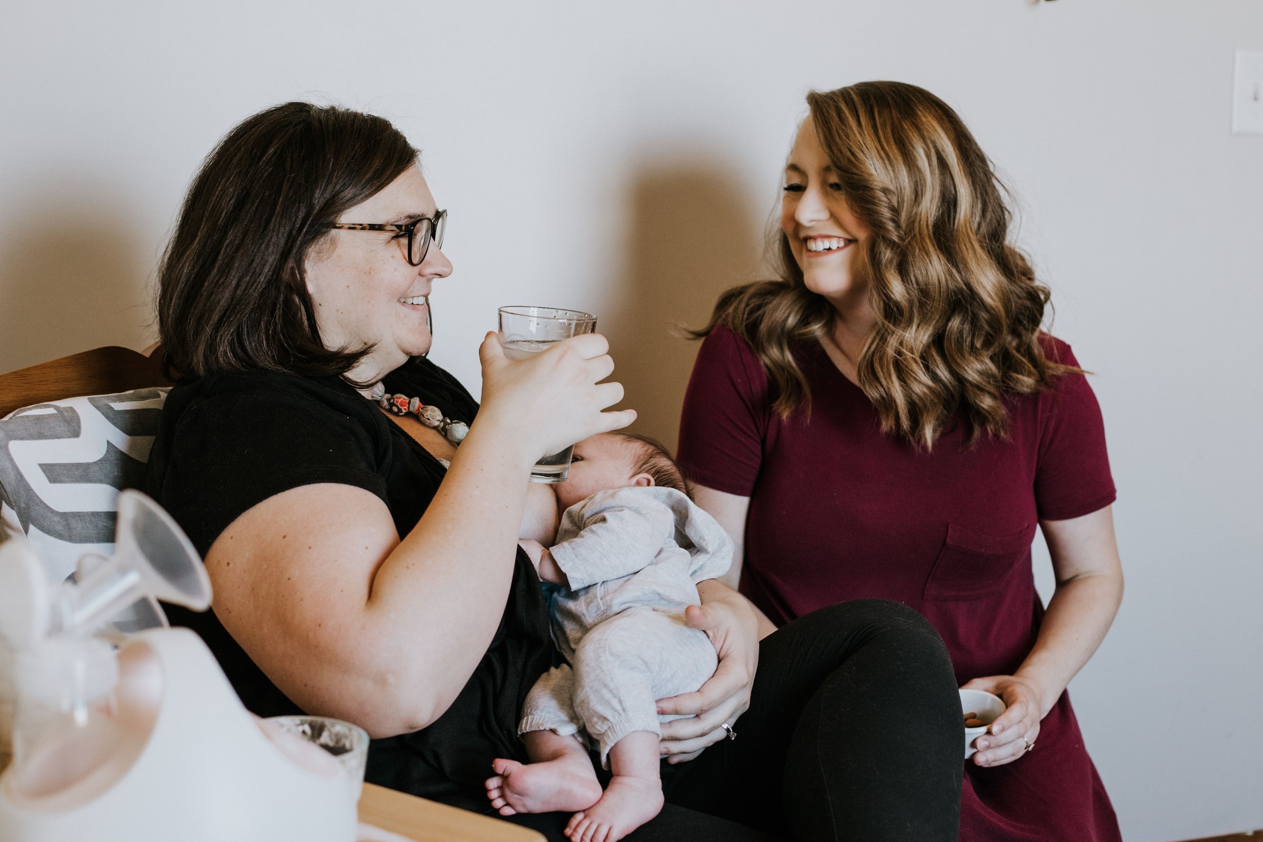 A mother holding her newborn baby while being attended to by her doula.