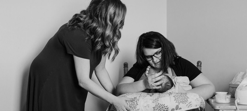 A mother nursing her baby while receiving lactation support from a doula