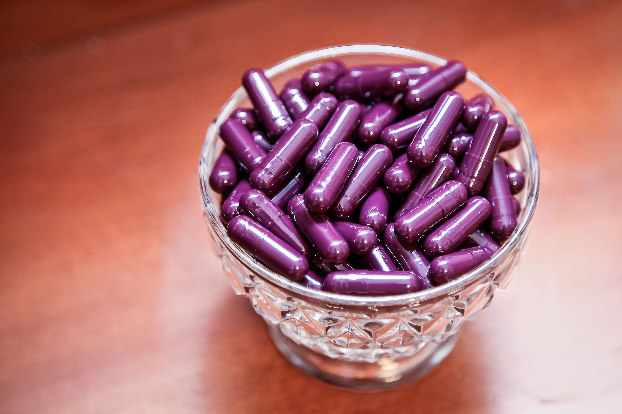A glass full of purple placenta capsules