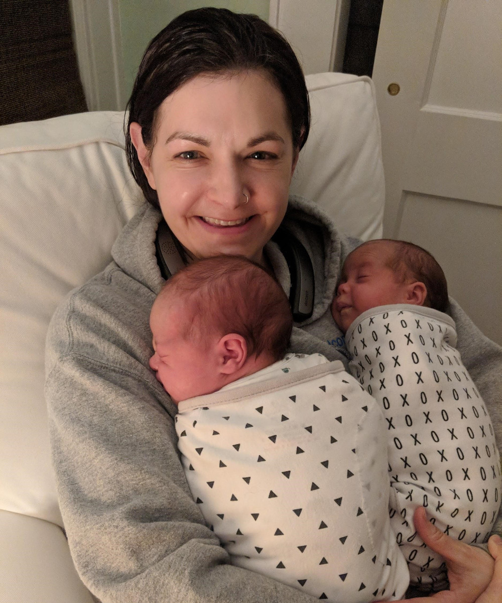 A postpartum doula holds a pair of twin babies overnight